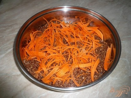 В глубокую сковороду, подходящую для использования в духовке, высыпаем промытую гречневую крупу. Сверху гречку слегка присыпаем солью. Морковь промываем, чистим, натираем на крупной терке или же мелко нарезаем. Затем распределяем измельчённую морковь поверх гречневой крупы.