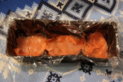 Пластиковую форму от печенья застелить пищевой плёнкой, выложить на дно слайсы копчёной рыбы.