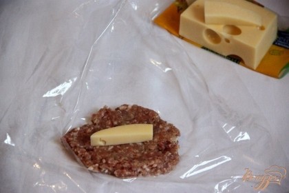 Сыр нарезать брусочками. На пищевую плёнку выложить 1-1,5 ст.л. фарша и разровнять, по центру - брусочек сыра