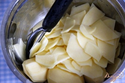 Картофель очистить, помыть и нарезать тонкими слайсами на специальной тёрке или овощечисткой.