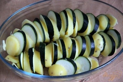 В подходящую форму для запекания выложить поочерёдно кабачки и картофель в вертикальном положении, ещё раз немного! посолить.