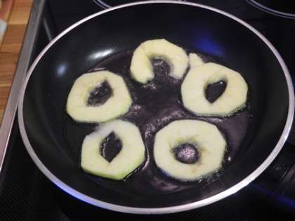 На горячую сковороду налить масло и выложить кружочки из яблок