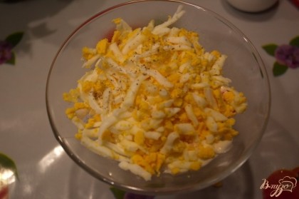 Отварите куриные яйца. Остудите. Очистив, натрите их на терку. Выложите следующим слоем в салатник, поверх крабовых палочек. Смажьте этот слой майонезом.
