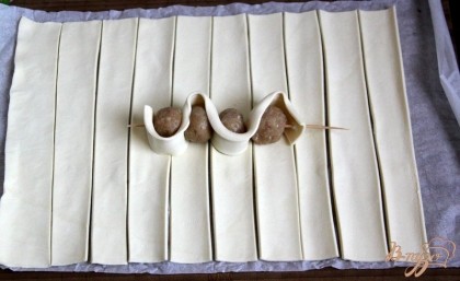 Слоёное тесто раскатать, нарезать полосками (ширина, как у мясных шариков) и надеть зигзагообразно тесто и шарики на шпажки