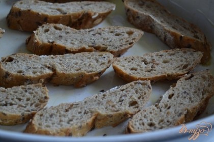 Форму для запекания смазать оливковым маслом и разложить кусочки хлеба.