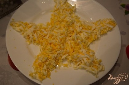 Отварите куриные яйца. Остудите. Очистите. Натереть их меленько или нарезать. Выложить на блюдо в форме звезды.