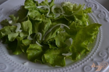 По тарелкам разложить салатные листья и репчатый лук.
