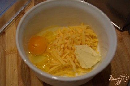 Переложите сыр в миску. Добавьте 1 яйцо, сливочное масло и соль, перец.