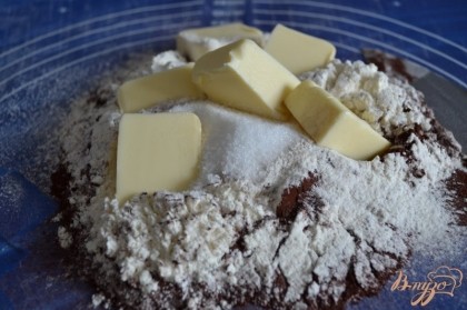 На  стол просеять муку, какао порошок, добавить сахар и соль.Выложить кусочки холодного сливочного масла. Порубить ножом до состояния крошки.
