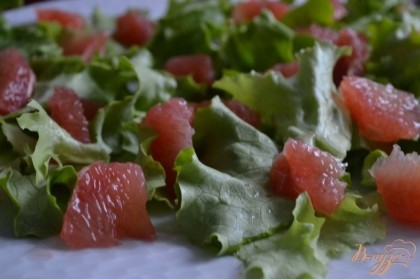 На большую, общую салатную тарелку разложить салатные листья и кусочки грейпфрута.