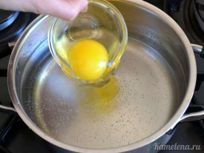 Яйцо вымыть горячей водой с мылом, затем аккуратно вбить в небольшую емкость. Когда со дна кастрюли начнут подниматься крупные пузырьки воздуха, поднести емкость к воде и плавно спустить яйцо в воду.