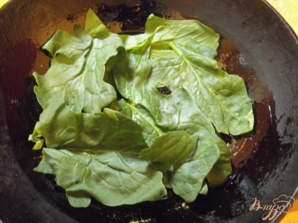 Чугунную сковородку или форму для выпекания смажьте растительным масло и выложите дно листьями шпината.