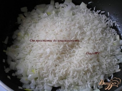 В это же время приготовить рис. На растительном масле обжарить лук и чеснок до мягкости, всыпать рис, готовить, помешивая, пока рис не станет прозрачным.