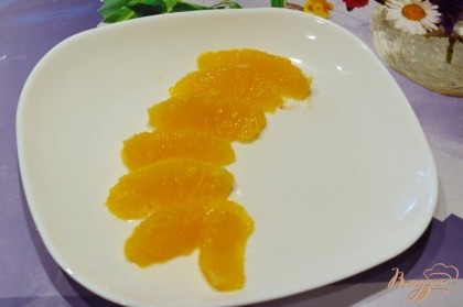 На порционную тарелку выкладываем дольки апельсина.