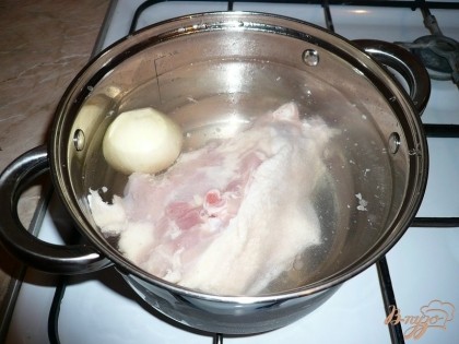 Для приготовления капустного супа с рисом первым делом надо приготовить наваристый бульон. Для него берём полностью остов курицы, окорочок или даже целого цыпленка. Куриное мясо как следует промываем, при необходимости избавляем от остатков перьев и лишнего жира. Затем кладем его в кастрюлю подходящего размера, заливаем холодной водой и ставим на огонь. Некрупную луковицу чистим и добавляем в кастрюлю. Если лук чистенький, то можно снимать не всю шелуху, оставить нижний слой, так бульон будет более красивого, золотистого цвета. По желанию в будущий бульон добавляем лавровый лист, черный перец горошком.