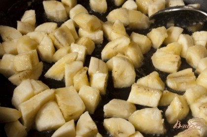 Тем временем бананы нужно почистить, нарезать небольшими ломтиками. Распустить на сковородке сливочное масло, добавить бананы и немного их обжарить.
