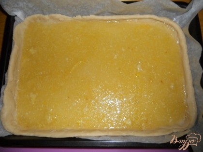 Разбиваем второе куриное яйцо отделяя белок от желтка. Большей частью белка смазываем пласт теста (дно будущего пирога). Выкладываем лимонную начинку на тесто.