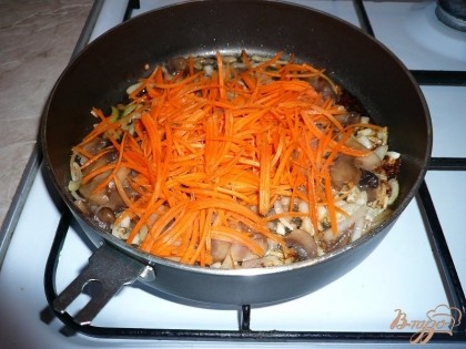 Морковь чистим, натираем на крупной терке или мелко нарезаем. Отправляем морковь на сковороду к луку и шампиньонам, продолжаем обжаривать все вместе, также регулярно помешивая.