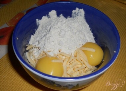 Куриные яйца разбиваем, отделяя желтки от белков. К натертому сыру добавляем желтки и две столовых ложки пшеничной муки.