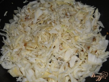 Когда лук приобретет золотистый цвет, добавляем в сковороду вторую ложку подсолнечного масла и выкладываем нарезанную капусту, перемешиваем и обжариваем их вместе. В процессе добавляем немного соли.