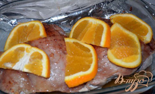 Через 40 минут после начала запекания вскройте фольгу. Проверьте мясо на готовность. Если мясо почти готово, преступаем к апельсину. Апельсин вымыть, разрезать пополам. Каждую половинку нарезать на дольки. Выложите апельсины поверх мяса. Снова затяните фольгой и поставьте в духовку. Запекать 15 минут.