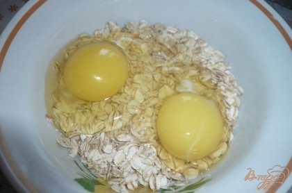 Высыпаем овсяные хлопья в небольшую плошку, заливаем их молоком, добавляем два яйца.