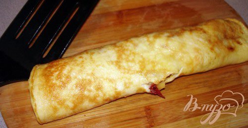 На одну сторону омлета выложите тертый на терку сыр. Сверните быстро омлет в рулет и дайте остыть слегка. Жар коржа расплавит сыр, а сыр в свою очередь скрепит слои омлетного рулета.