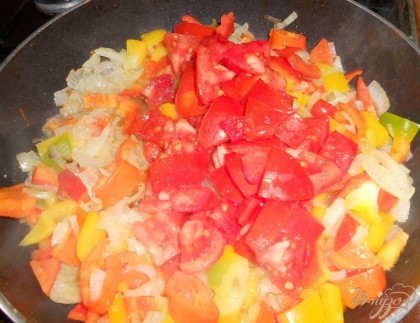Добавляем помидоры к луку и болгарскому перцу, продолжаем обжаривать овощи, регулярно их помешивая.