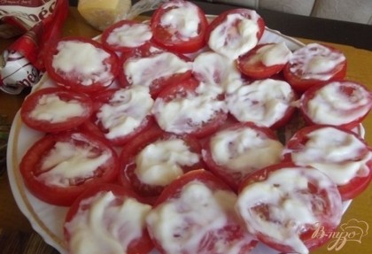 При помощи ложки смажьте каждый помидор обильно заправкой после чего сверху равномерно посыпьте чесноком с укропом.