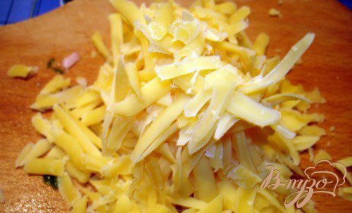Теперь приготовьте твердый сыр. Его следует освободить от упаковки и парафина-воска. Натереть на крупной терке. Твердый сыр можно и нарезать руками соломкой, но в этом случае он будет более жесткий в салате. Добавьте сыр к компонентам салата.