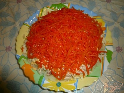 Если морковь по-корейски очень длинной соломкой, то нарезаем её помельче. Выкладываем морковь на куриное мясо.