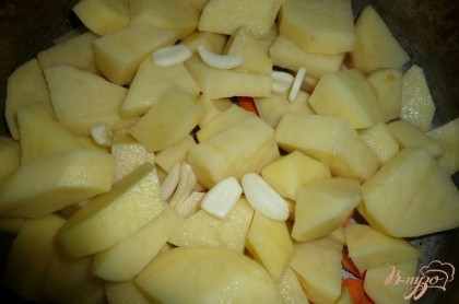Далее берем две-три дольки чеснока, чистим их, разрезаем на несколько частей и добавляем в сковороду к картофелю и моркови.