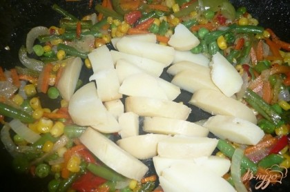 На сковороду к овощной смеси выкладываем дольки отварного картофеля.