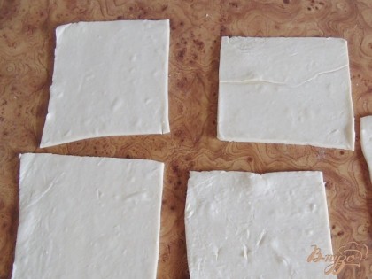 Размороженное готовое слоеное тесто тонко раскатываем, режим на квадраты по 10 сантиметров.