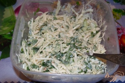 Соедините огурцы, капусту, зелень. в едином салатнике. Заправьте все сметаной. Добавьте соль и специи. Хорошо перемешайте. Салат почти сразу начнет давать сок.