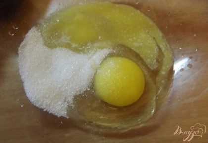 Дальше приготовьте тесто для коржа. Взбейте одно куриное яйцо с сахаром и столовой ложкой растопленного сливочного масла.