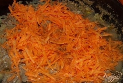 Когда мясо побелеет со всех сторон, можно выложить сверху морковь. Ее нужно натереть на крупной терке.