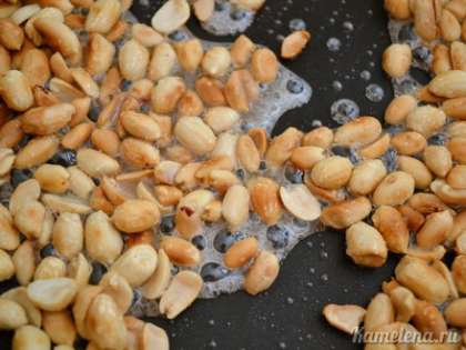 Вернуть арахис на сковороду и добавить сахар с водой.  Готовить на среднем огне, непрерывно перемешивая.