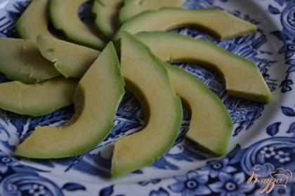 По тарелкам разложить ломтики авокадо и на них салатную смесь.
