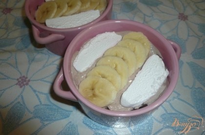 На крем выкладываем отложенный зефир и нарезанный банан.