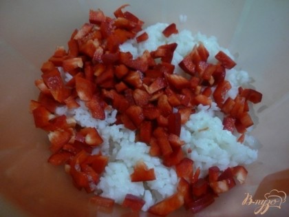 Сладкий болгарский перец промываем, освобождаем от плодоножки и семян, затем нарезаем мелкими кубиками. Рис выкладываем в глубокую миску, добавляем к нему нарезанный болгарский перец.