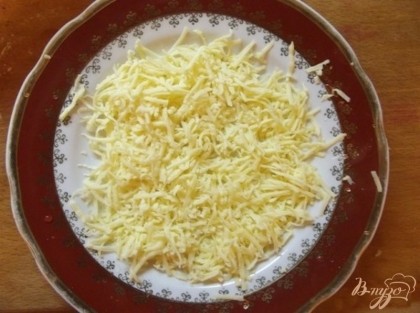 Дальше подготовьте половину сыра в салат следующим образом. Натрите его на мелкой терке в блюдечко, смазанное растительным маслом, разровняйте ровным слоем и смажьте немного сметаной или майонезом, равномерно.