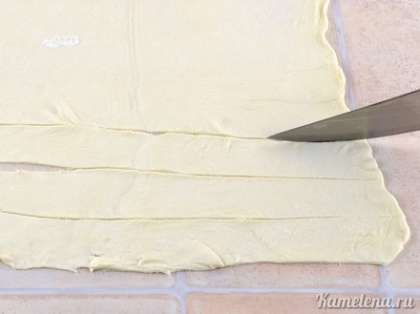 Размороженное тесто тонко раскатать (1-2 мм по толщине). Порезать на полосы 3 см по ширине и 25-30 см по длине.