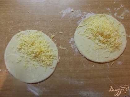 Сыр натрите на мелкой терке. Мысленно поделите кружочки из теста на полукруги и засыпьте их сыром.