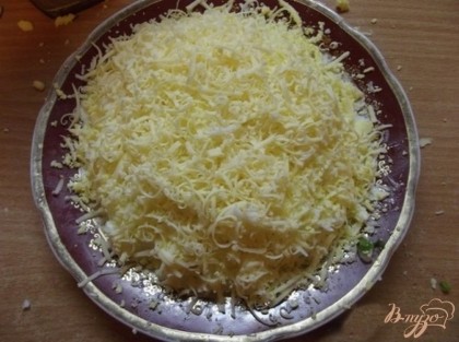 Поверх желтков натрите снова на мелкой терке твердый сыр. Сверху салат украсьте зеленым луком и подавайте холодным к праздничному столу.