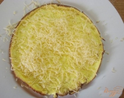 Горячий омлет выложите аккуратно лопаткой на блюдо и сразу натрите на мелкой терке сыр. Само собой, чем больше сыра, тем вкуснее будет блюдо.