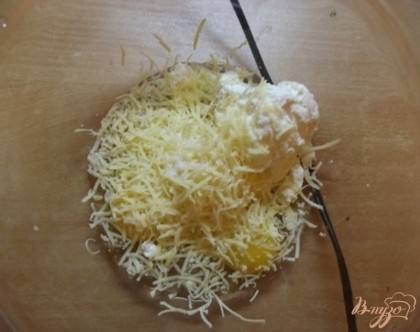К творогу и яйцам добавьте натертый на мелкой терке сыр. После немного взбейте массу миксером.