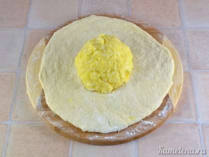 Вытянуть тесто в большую лепешку (подсыпая муку при необходимости). В центр лепешки положить шар начинки.