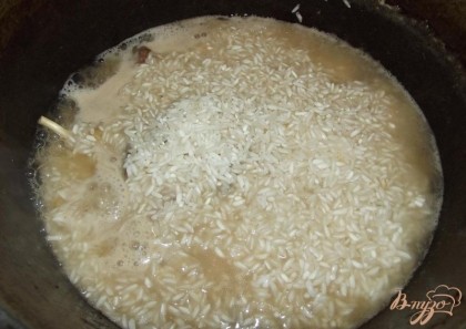 Когда вода в мясе закипит, всыпьте рис и при помощи ложки выложите его сверху ровным слоем. При этом ни в коем случае нельзя перемешивать! Сверху рис посолите по вкусу. Куркуму необходимо добавить примерно через 3-5 минут после того, как вы положите в казанок рис. Не накрывая крышкой на большом огне варите плов постоянно подливая горячую воду, чтобы рис оставался под водой. Когда рис будет готов (нужно пробовать) уменьшите газ и дайте воде выкипеть.