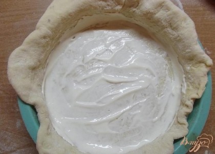 Положите тесто в сухую форму так, чтобы его края слегка вылезали из нее. Смажьте тесто на дне сметаной (2 ст.л.).